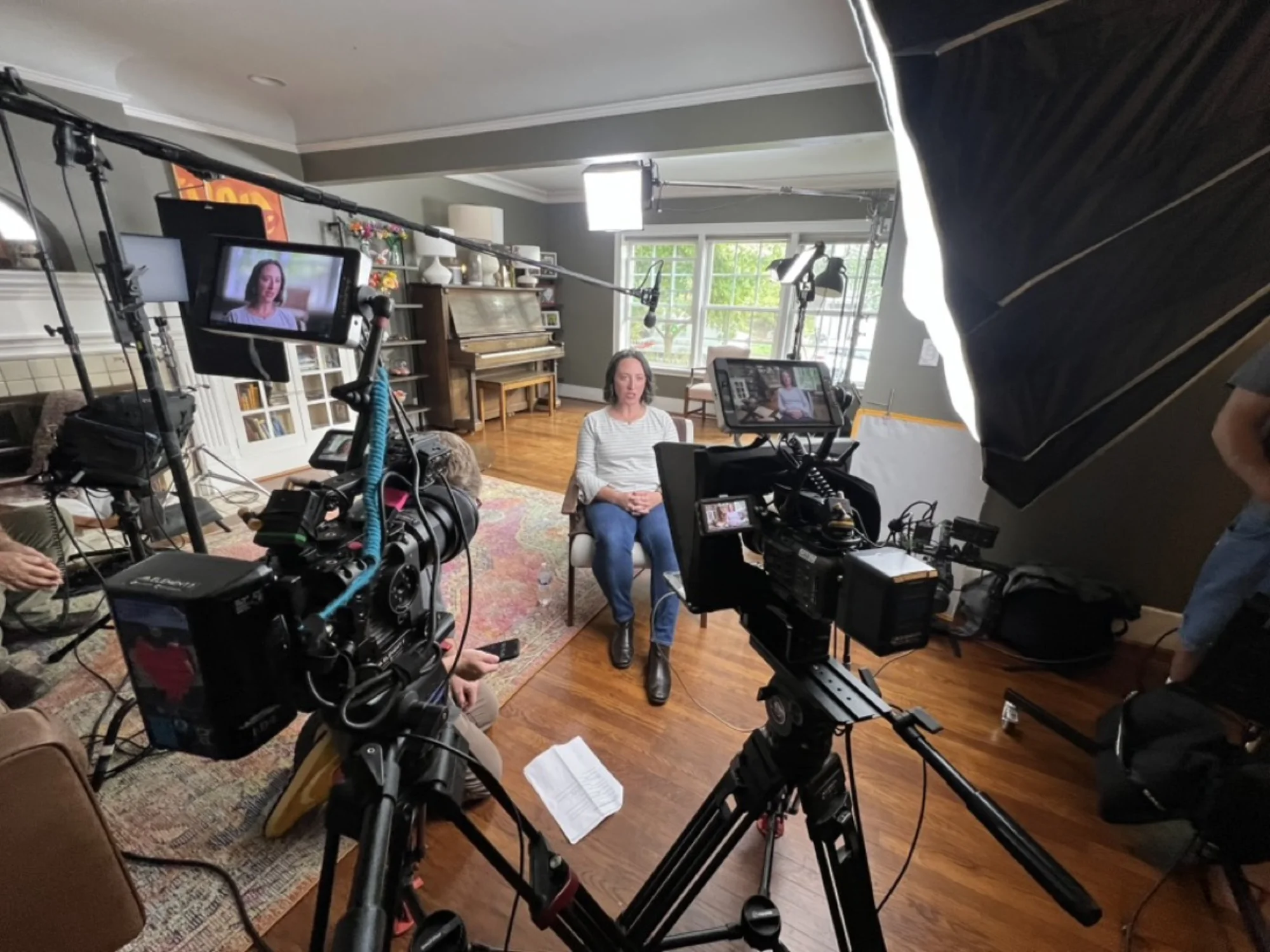 Documentary interview setup in home — dual cameras, boom, lighting, monitors
