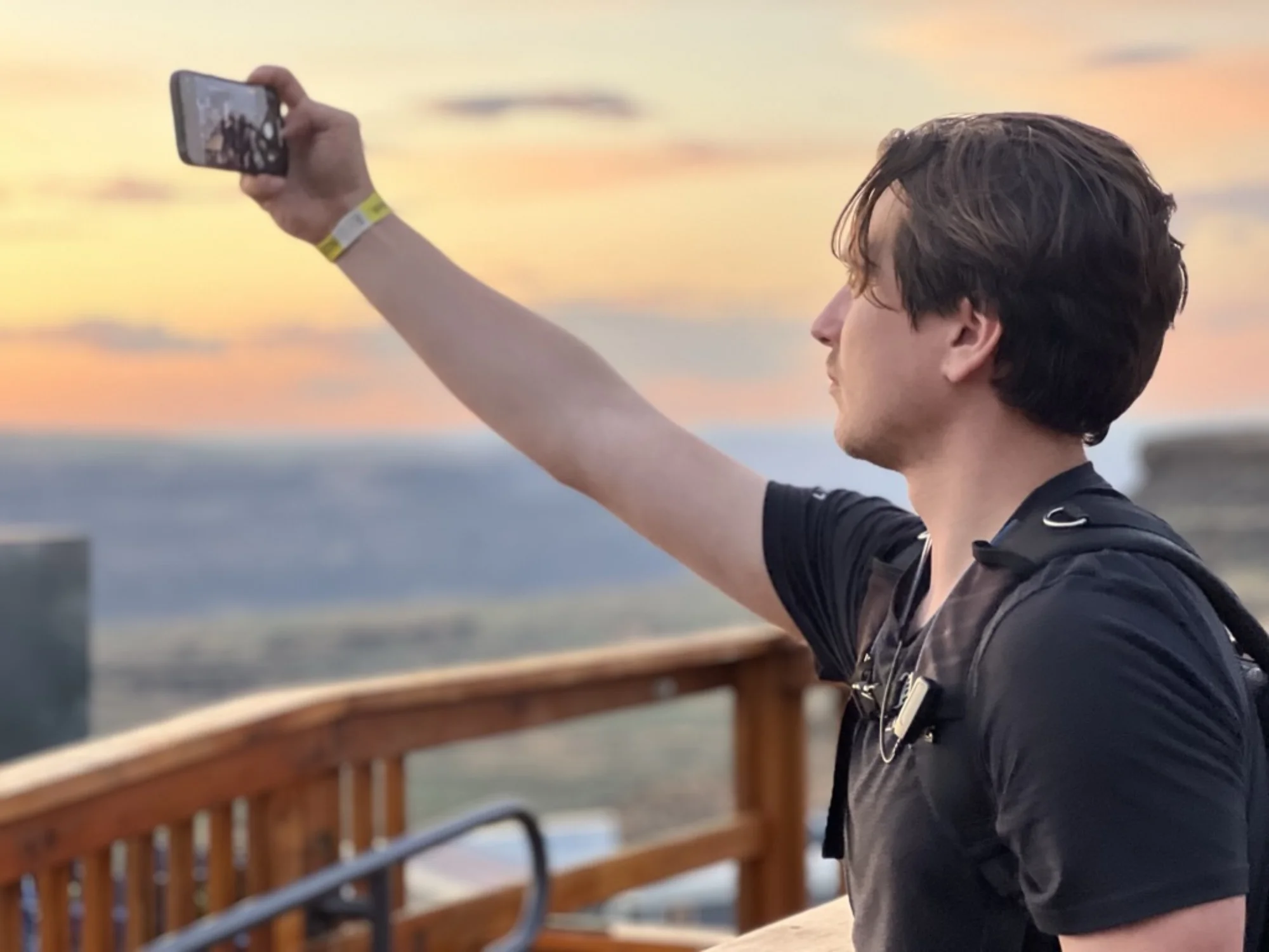 Event attendee capturing social content on phone at sunset